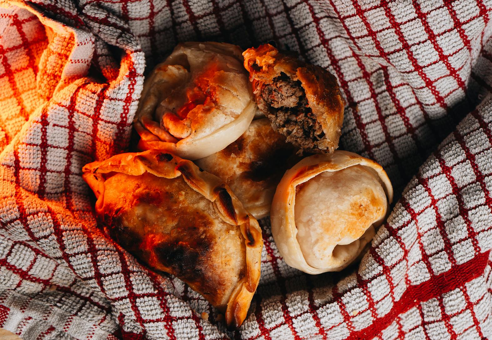 Close-up of Argentine empanadas on a red checked cloth, highlighting their golden crust.