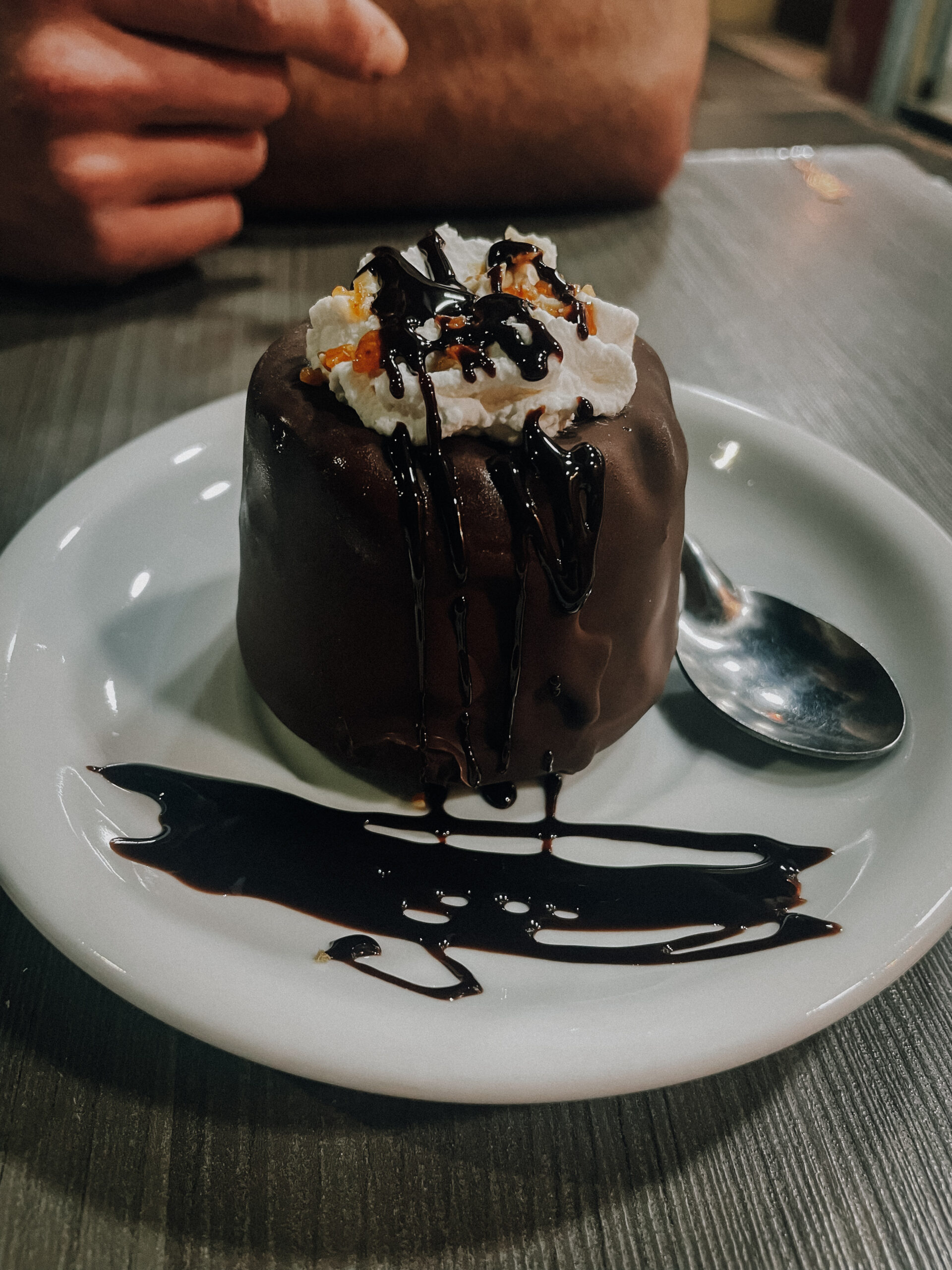 Dessert of ice cream scoop covered in layer of hardened chocolate and chocolate drizzle