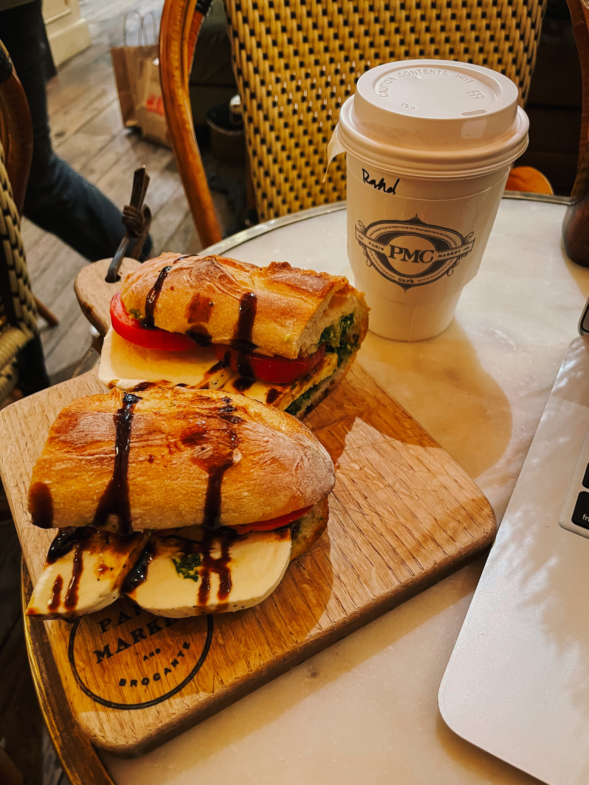 Baguette sandwich next to paper coffee cup at Paris Marlet