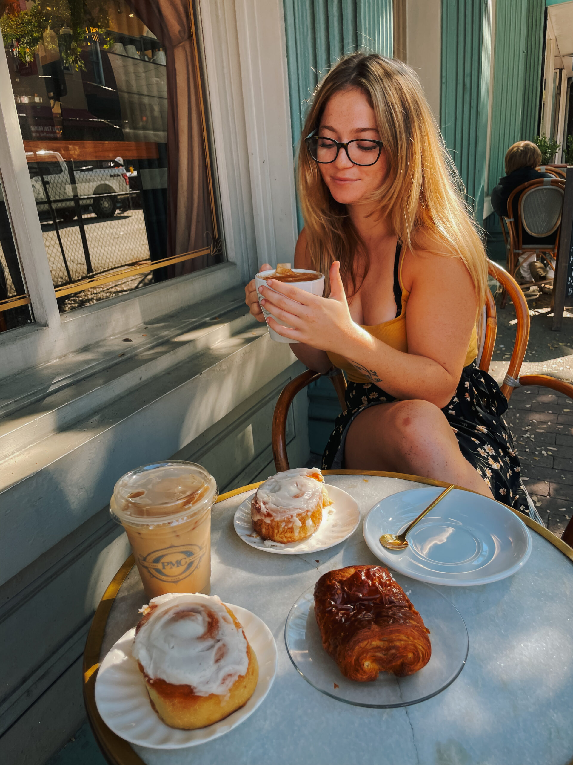 Me sitting in front of table with coffee and pastries at Paris market in Savannah