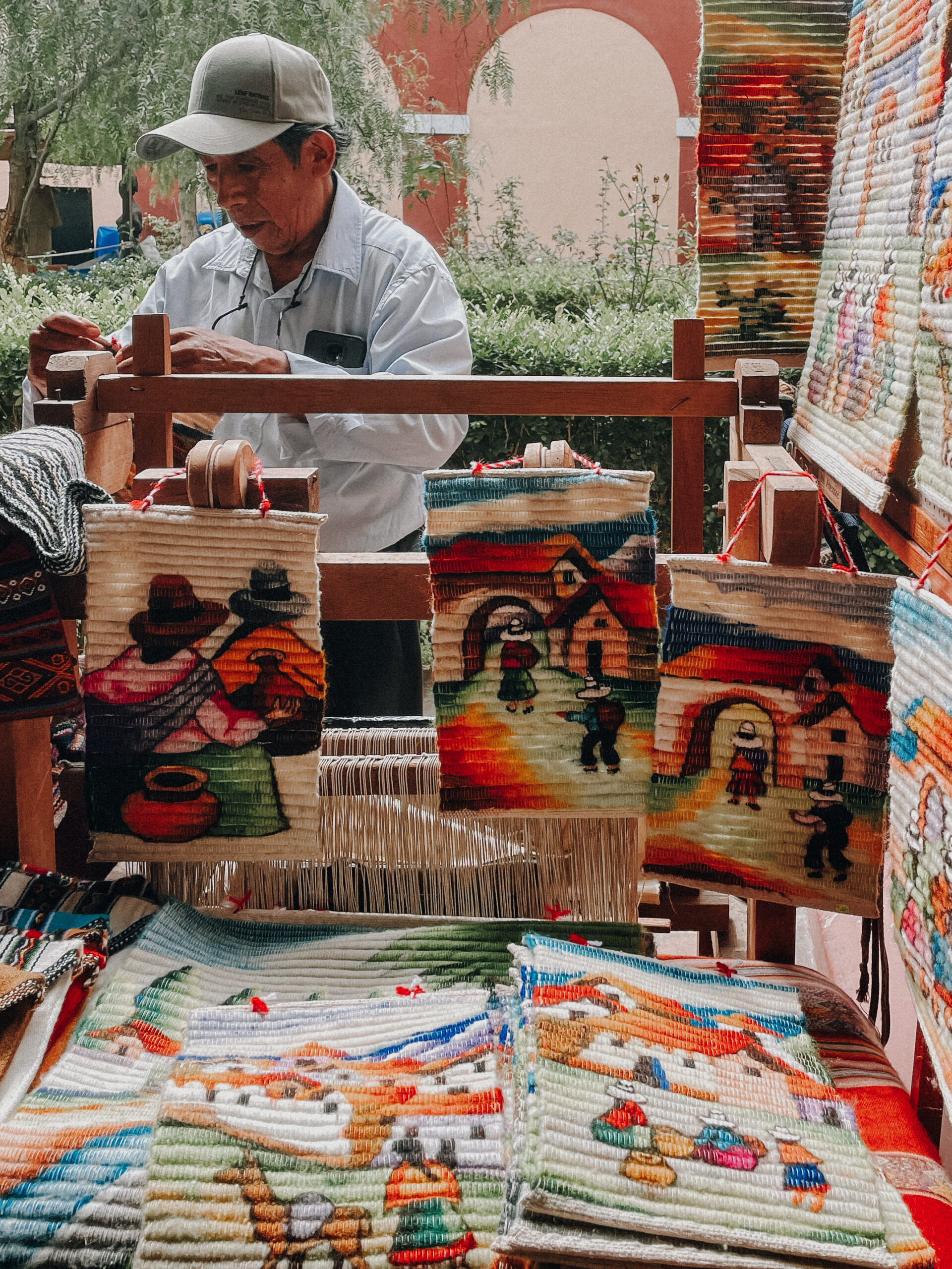 Man showcasing colorful hand-woven tapestries